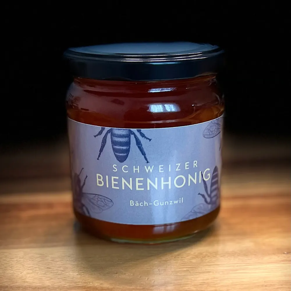 Geschlossenes 500-Gramm-Glas Schweizer Bienenhonig von Bienen Naef mit hellblauer Etikette auf einer Holzoberfläche